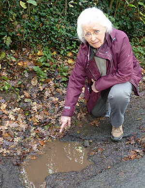 Cllr Gill Moseley points out a pothole that urgently needs repair by Gloucestershire County Council